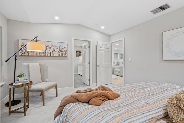 bedroom featuring ensuite bath, vaulted ceiling, and light carpet