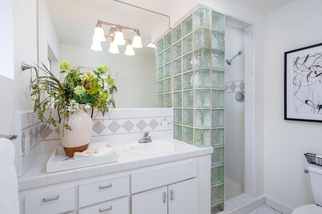 bathroom featuring a tile shower, vanity, and toilet