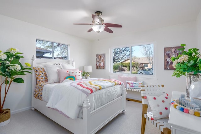 carpeted bedroom featuring multiple windows and ceiling fan