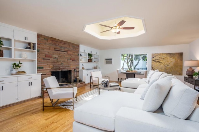 living room with light hardwood / wood-style flooring, a fireplace, built in features, and ceiling fan