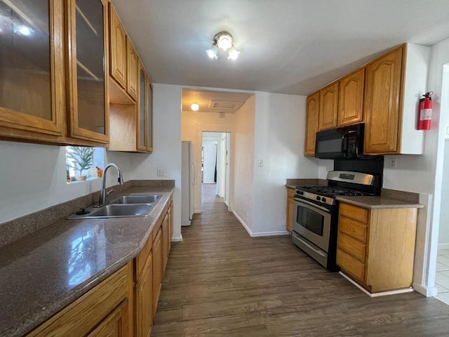 kitchen with dark wood-type flooring, stainless steel range with gas stovetop, sink, and dark stone countertops