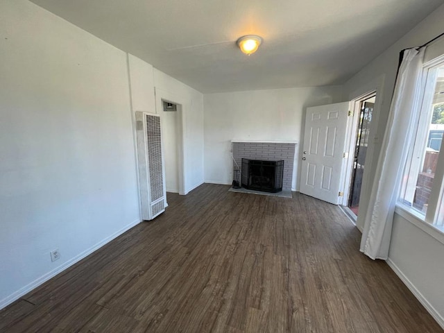 unfurnished living room with dark hardwood / wood-style flooring and a brick fireplace