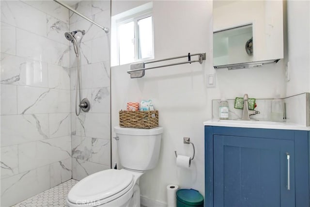 bathroom with tiled shower, vanity, and toilet