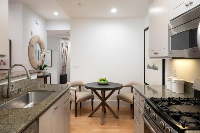 kitchen featuring dark stone countertops, sink, white cabinets, and appliances with stainless steel finishes