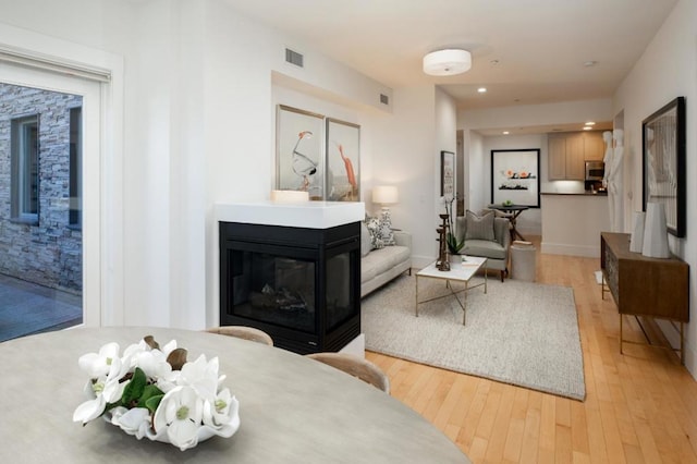 sitting room with a multi sided fireplace and light hardwood / wood-style floors