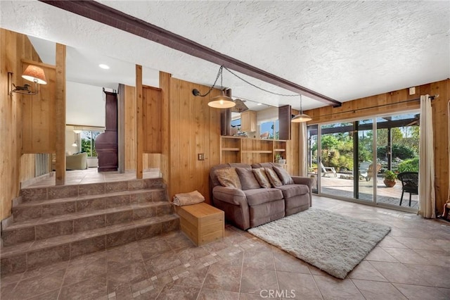 living room with a textured ceiling, wooden walls, and beamed ceiling