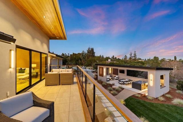 balcony at dusk featuring an outdoor living space with a fire pit