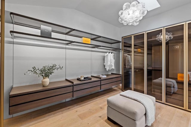 spacious closet with vaulted ceiling, hardwood / wood-style floors, and a notable chandelier