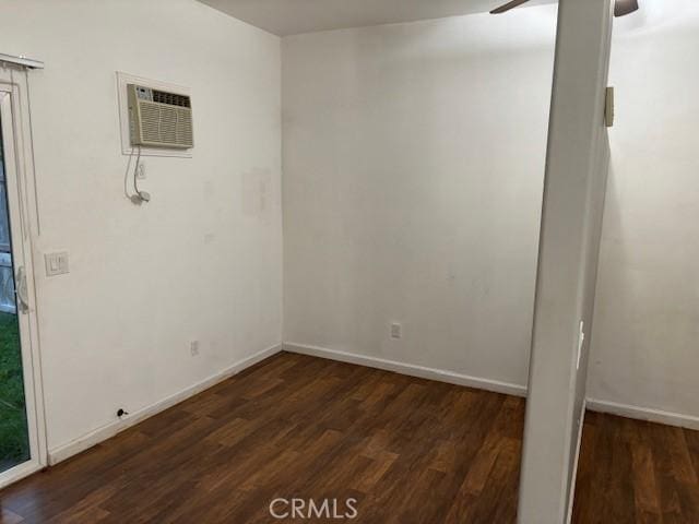 spare room featuring dark wood-type flooring, a wall mounted air conditioner, and ceiling fan