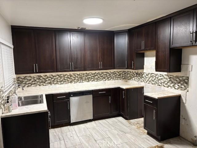 kitchen with dark brown cabinetry, sink, decorative backsplash, and stainless steel dishwasher