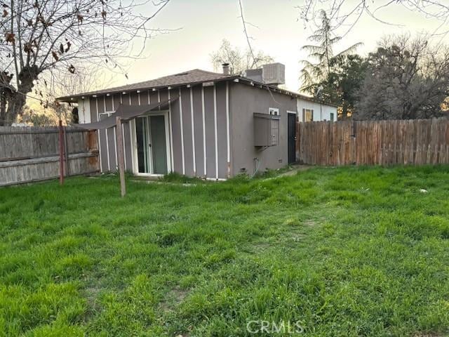 back house at dusk featuring a yard and central AC