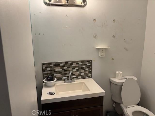 bathroom featuring tasteful backsplash, vanity, and toilet