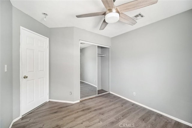 unfurnished bedroom featuring ceiling fan, wood-type flooring, and a closet