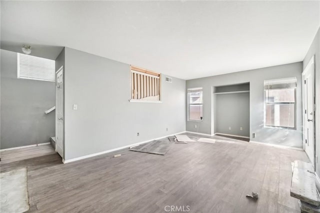 unfurnished bedroom with multiple windows, wood-type flooring, and a closet