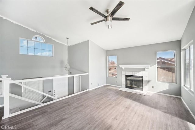 unfurnished living room featuring wood-type flooring, lofted ceiling, ceiling fan, and a fireplace