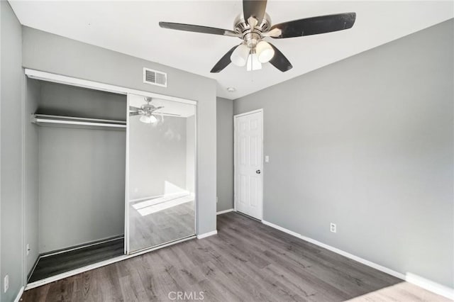 unfurnished bedroom with wood-type flooring, ceiling fan, and a closet