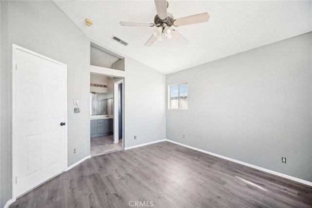 unfurnished bedroom with lofted ceiling, hardwood / wood-style floors, ceiling fan, and ensuite bathroom