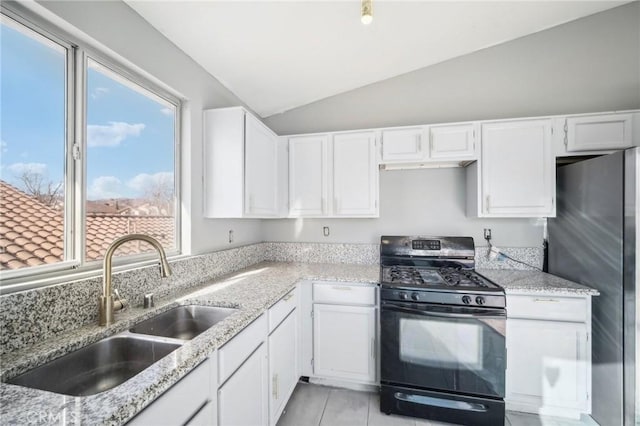 kitchen with sink, white cabinetry, vaulted ceiling, black range with gas stovetop, and stainless steel fridge