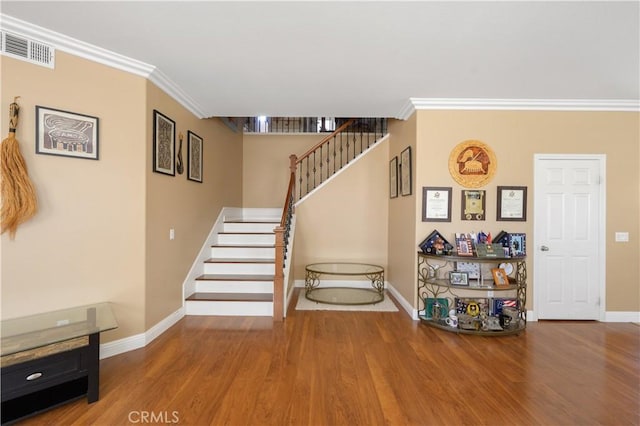 staircase with hardwood / wood-style floors and ornamental molding