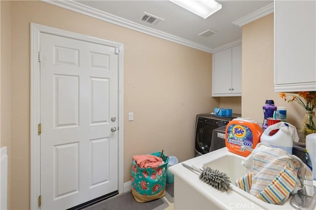 clothes washing area with cabinets, ornamental molding, and washer and clothes dryer