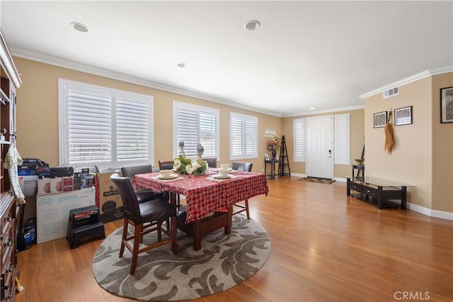 dining area with ornamental molding and light hardwood / wood-style floors