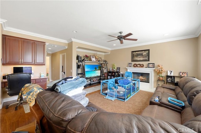 living room with built in desk, ornamental molding, and ceiling fan