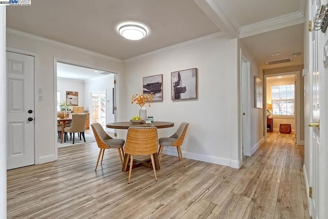 dining space with crown molding and light hardwood / wood-style floors