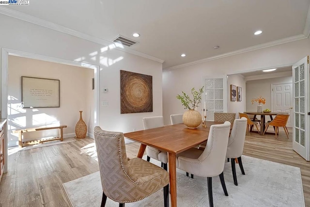 dining space featuring crown molding, light hardwood / wood-style floors, and french doors