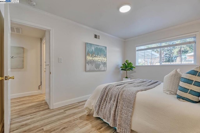 bedroom featuring ornamental molding and light hardwood / wood-style flooring