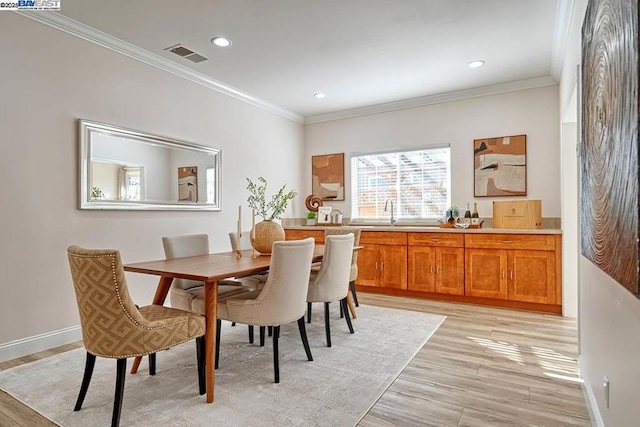 dining area with sink, ornamental molding, and light hardwood / wood-style floors