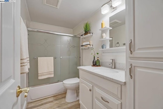 full bathroom with vanity, wood-type flooring, combined bath / shower with glass door, and toilet