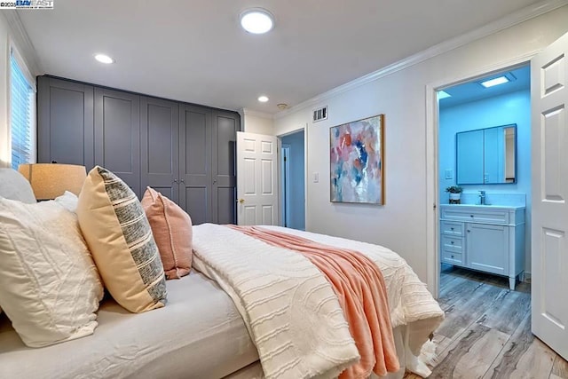 bedroom featuring sink, crown molding, light hardwood / wood-style flooring, and ensuite bath