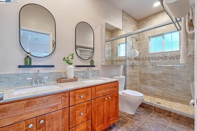 bathroom with a shower with door, vanity, and toilet