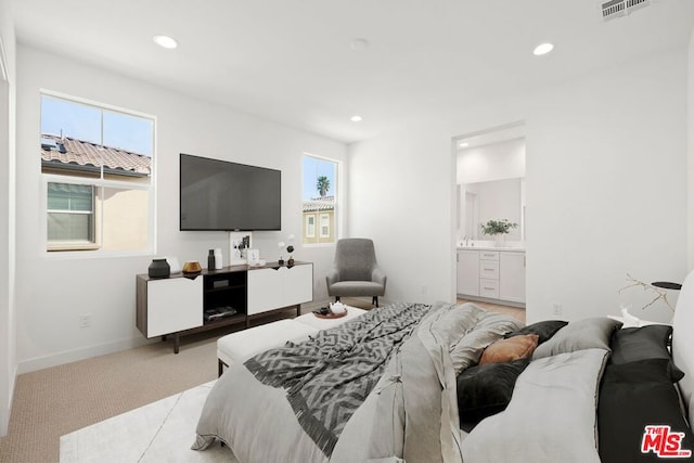 bedroom with light colored carpet and ensuite bath