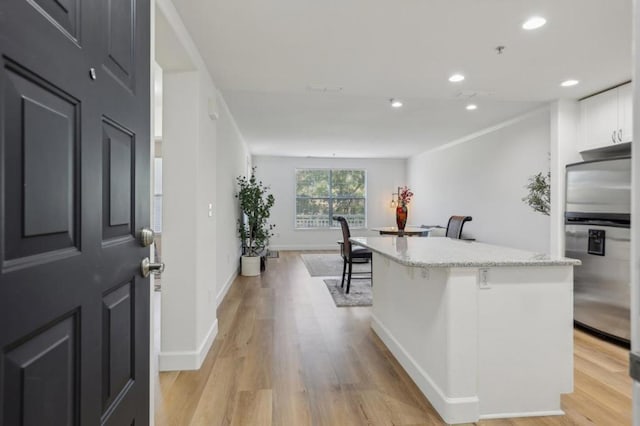 kitchen featuring white cabinetry, a kitchen bar, light hardwood / wood-style flooring, and stainless steel refrigerator with ice dispenser