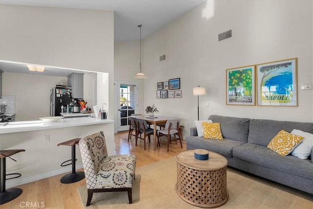 living room featuring high vaulted ceiling, visible vents, and light wood-style flooring