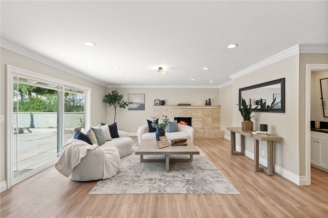 living room featuring ornamental molding, a tile fireplace, and light wood-type flooring