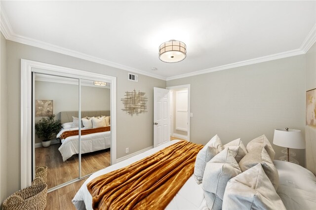 bedroom featuring crown molding, light hardwood / wood-style floors, and a closet