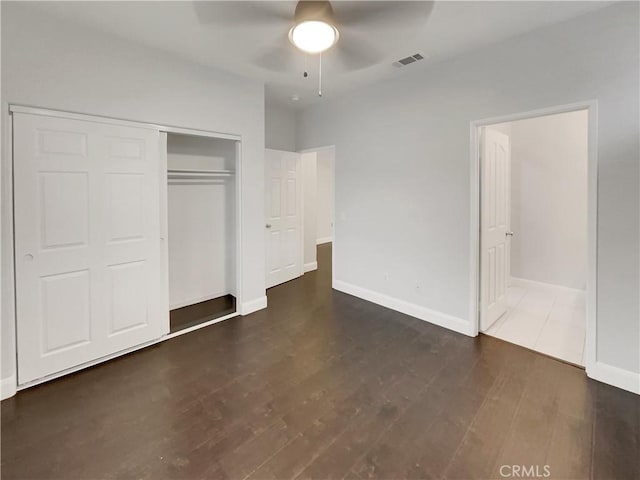 unfurnished bedroom with a closet, visible vents, baseboards, and wood finished floors