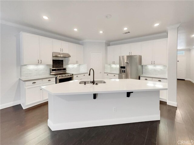 kitchen with sink, a kitchen island with sink, stainless steel appliances, ornamental molding, and white cabinets