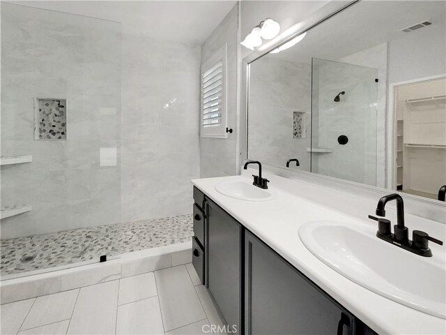 bathroom with tiled shower, vanity, and tile patterned flooring