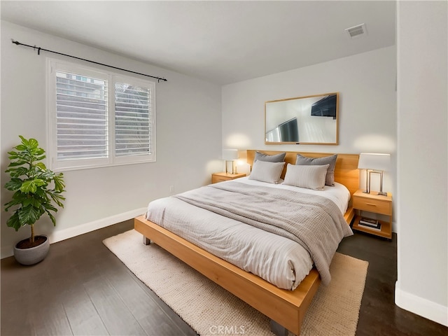 bedroom featuring visible vents, baseboards, and wood finished floors