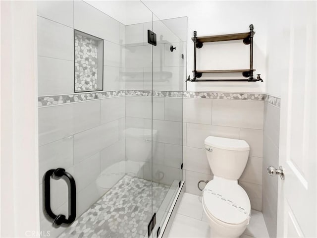 full bathroom with a baseboard radiator, toilet, a wainscoted wall, tile walls, and a stall shower