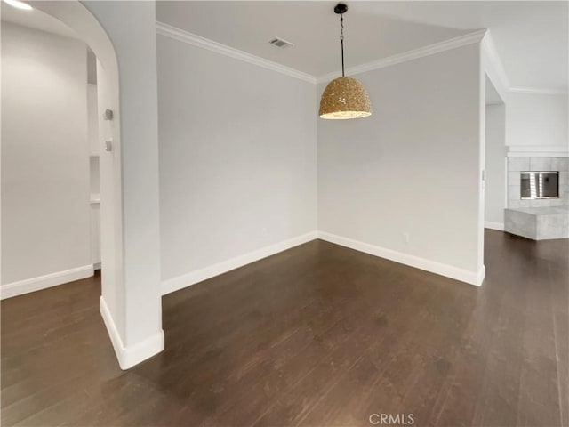 unfurnished dining area featuring arched walkways, dark wood-style flooring, visible vents, and baseboards