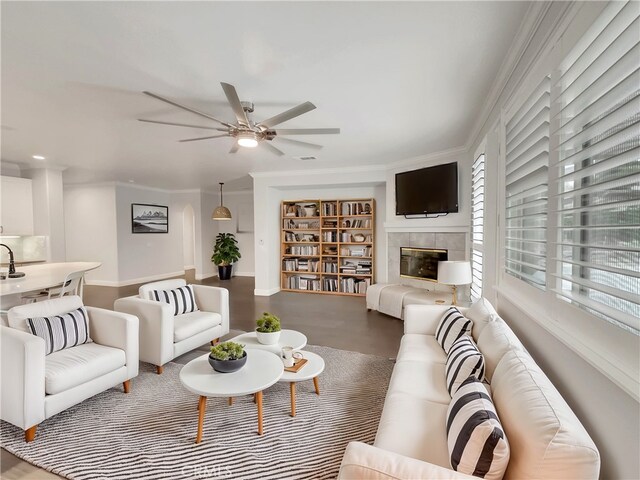 living room featuring sink, ornamental molding, a tile fireplace, hardwood / wood-style flooring, and ceiling fan