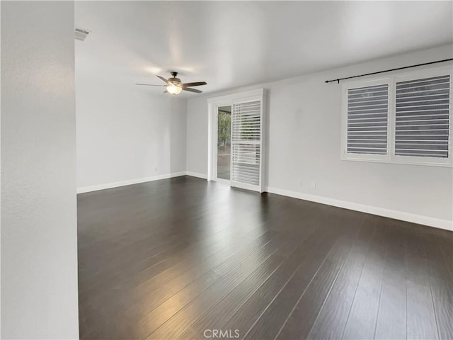 spare room featuring dark wood-style flooring, visible vents, ceiling fan, and baseboards