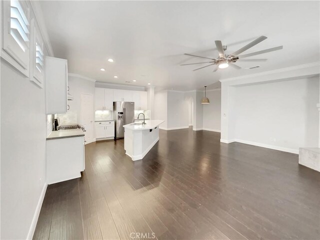 interior space featuring high end fridge, a kitchen island with sink, white cabinets, dark hardwood / wood-style flooring, and decorative light fixtures