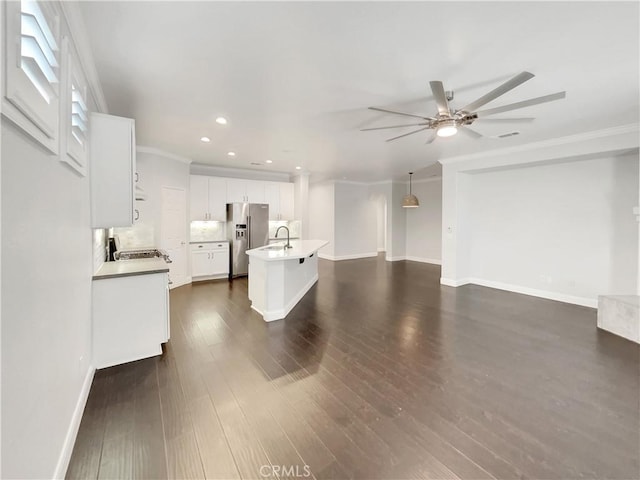 unfurnished living room featuring baseboards, a ceiling fan, dark wood-type flooring, crown molding, and a sink