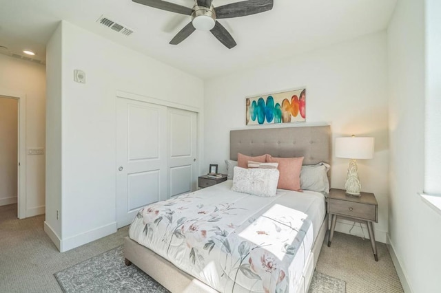 bedroom featuring light colored carpet, a closet, and ceiling fan