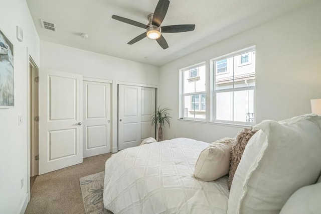 carpeted bedroom featuring two closets and ceiling fan